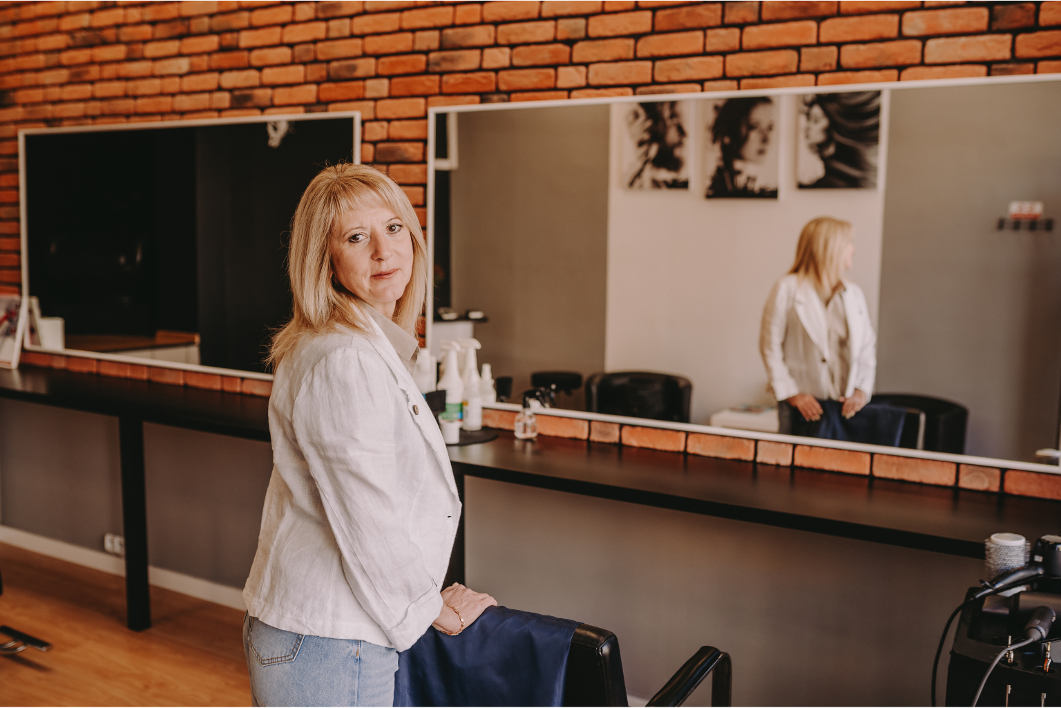 Olena Pavlenko w salonie fryzjerskim w Szczecinie, oparta o fotel, gotowa do pracy