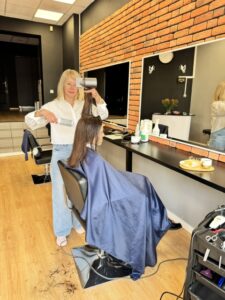Olena Pavlenko stylizuje włosy klientki w salonie Ameliia